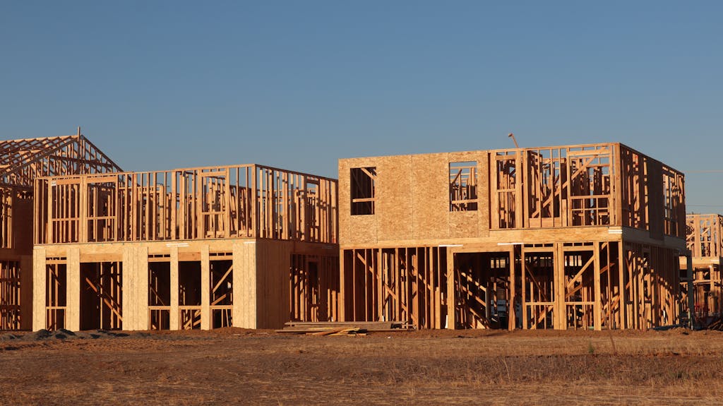 Wooden frames of new homes under construction in Elk Grove, California, during daylight.